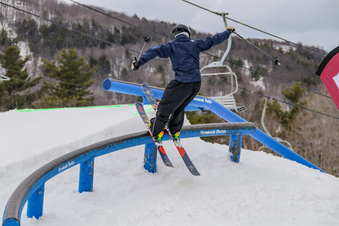Skier rides a blue parks rail.