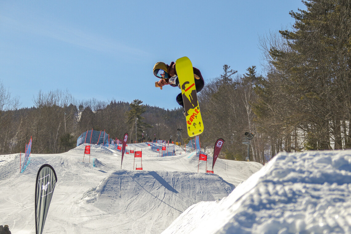 Snowboarder jumps through a slalom course.