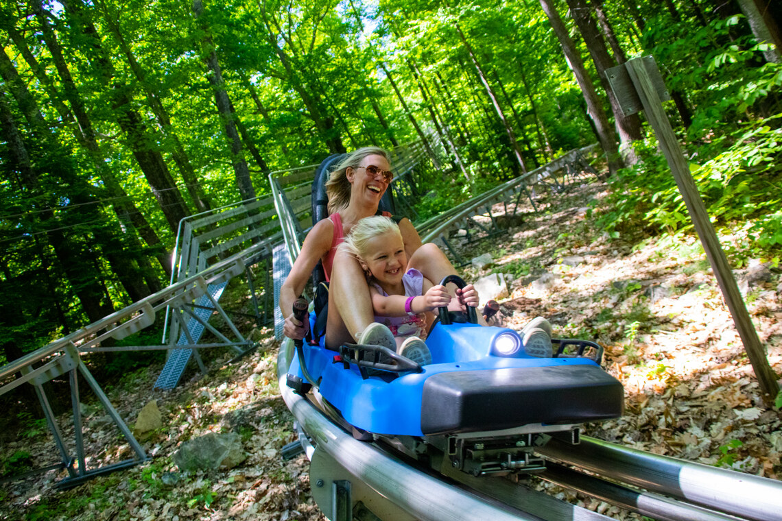 Mom and daughter riding the mountain coaster in the summer